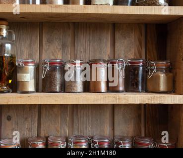 Bottiglie con spezie e condimenti in rack di legno. Varie erbe organiche diverse per nella cucina vintage guardare molti Foto Stock