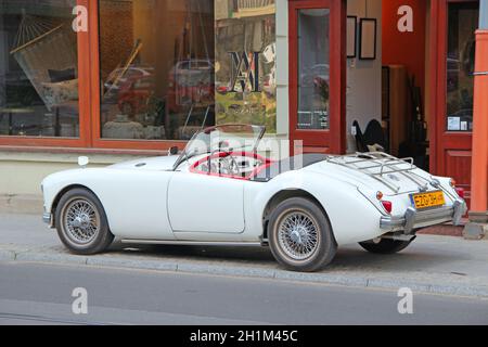 MG auto cabriolet sulla strada di Lodz. Auto bianca MG cabriolet in piedi sul marciapiede della strada cittadina a Lodz. Carroadster bianco convertibile MGA da 1960 MG parcheggiato su ci Foto Stock