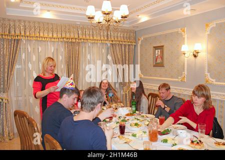 Gli ospiti si sono riuniti al tavolo delle feste. Persone felici che siedono al tavolo delle feste. Le persone che si divertano con la festa festiva al ristorante. Festa di famiglia cele Foto Stock