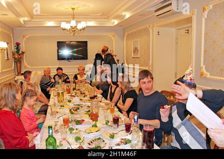 Gli ospiti si sono riuniti al tavolo delle feste. Persone felici che siedono al tavolo delle feste. Le persone che si divertano con la festa festiva al ristorante. Festa di famiglia cele Foto Stock