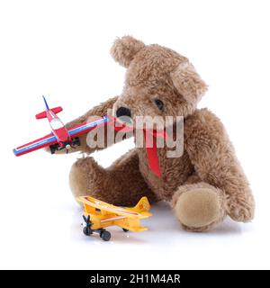 Un piccolo peluche carino che gioca con aerei giocattolo Foto Stock