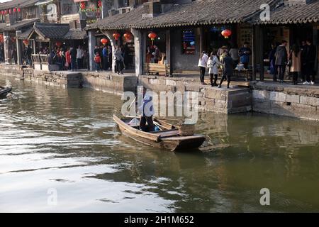 Uomo in una barca di legno sui canali d'acqua della città di Xitang nella provincia di Zhejiang, Cina Foto Stock