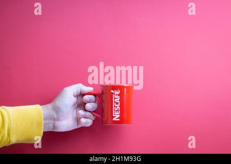 Kuala Lumpur, Malesia - 12 novembre 2020 : mano che tiene Nescafe Mug su sfondo rosso Foto Stock