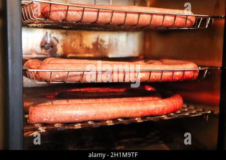 Primo piano di vassoi di salsiccia in un fumatore. Foto Stock