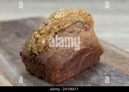 Pane di banana appena sfornato scorfito con burro di pistacchio e servito su un piatto di legno. Foto Stock