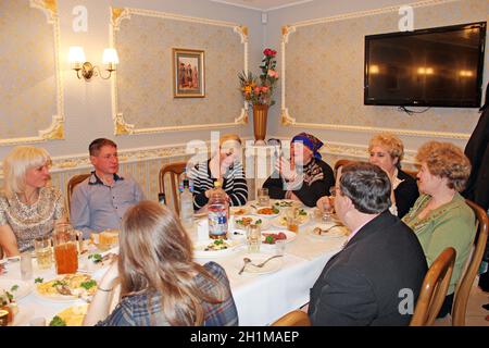 Gli ospiti si sono riuniti al tavolo delle feste. Persone felici che siedono al tavolo delle feste. Le persone che si divertano con la festa festiva al ristorante. Festa di famiglia cele Foto Stock