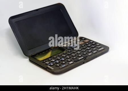 Vecchio organizer elettronico con display a cristalli liquidi con la linguetta aperta isolata su uno sfondo bianco. Tecnologia obsoleta degli anni '90 Foto Stock