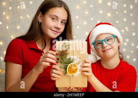 Una ragazza con sindrome di Down e la sua sorella più anziana stanno imballando i regali di Natale Foto Stock