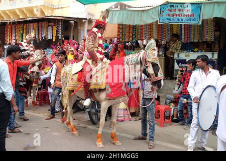 Il giovane sposo su un cavallo conduce la festa di nozze alla casa della sposa in Pushkar, Rajasthan, India Foto Stock