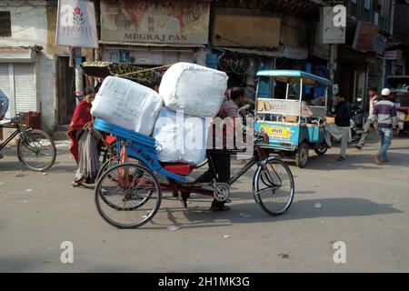 Gli indiani che lavorano duramente spingono carichi pesanti attraverso le strade di Delhi, India Foto Stock