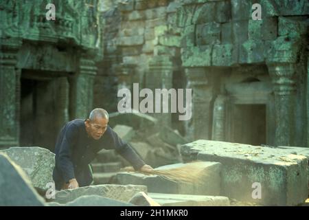 Gli uomini vecchi con il nome Prohm sta clining il tempiale con il suo nome Ta, gli uomini vecchi e il suo secondo nome Prohm. Mister Ta Prohm nel tempio Ta Prohm in Foto Stock