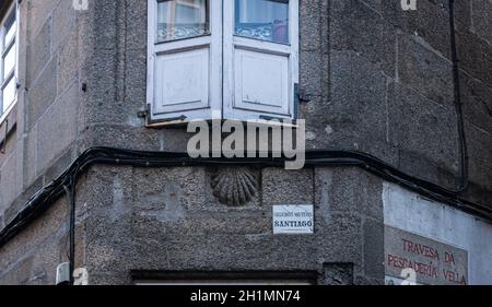 La conchiglia del capesante simbolo del Camino de Santiago e un cartello assicurativo su un edificio, nella città di Santiago de Compostela, Spagna Foto Stock