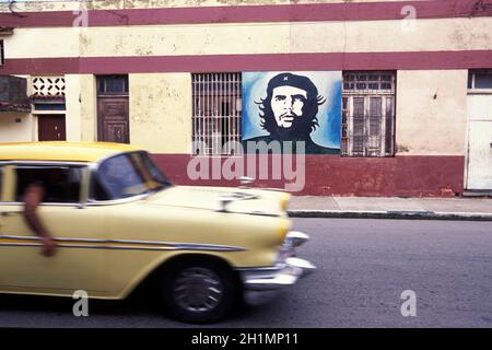 Una foto di che Guevara su un muro e una vecchia auto americana su una strada nella città di l'Avana su Cuba nel mare dei caraibi. Cuba, l'Avana, ottobre 2005 Foto Stock