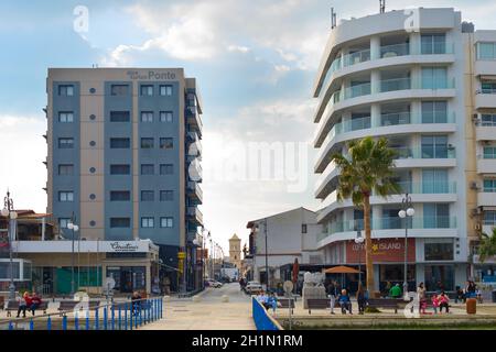 LARNAKA, CIPRO - FEB 18, 2019: Persone a piedi dal lungomare della città di Larnaca. Edifici dell'hotel. Chiesa di San Lazzaro sullo sfondo. Cipro Foto Stock