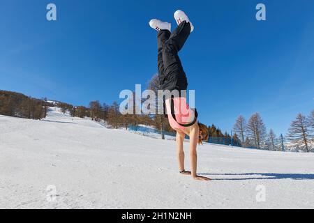 Donna che gode di tempo soleggiato su una pista da sci, luce del sole calda, snowboarder femminile, facendo il cavalletto Foto Stock