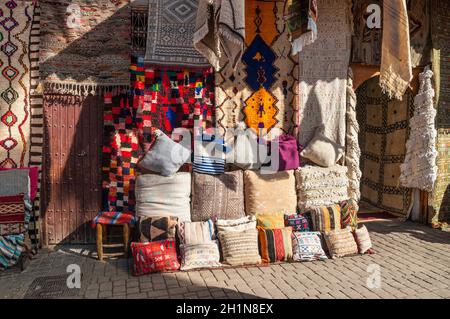 Marrakech, Marocco - 8 Dicembre 2016: Prodotti Tessili per la vendita nel famoso souk di Marrakech, Marocco, Africa. I raggi del sole sui tappeti. Foto Stock