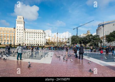 Barcellona, Spagna - 5 Dicembre 2016: turisti alimentare i piccioni sulla piazza di Catalogna (Plaça de Catalunya) a Barcellona. Plaza de Catalunya è uno Foto Stock