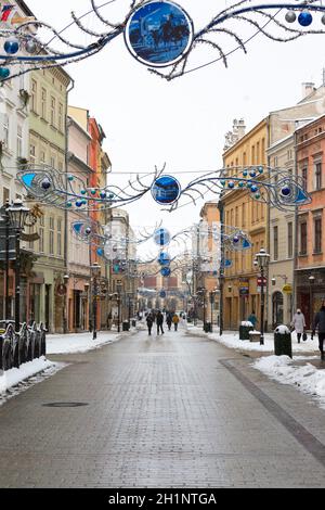 Cracovia, Polonia - 17 gennaio 2021: Inverno nevoso a Cracovia, poche persone che camminano su Grodzka Street. Decorazione di Natale Foto Stock