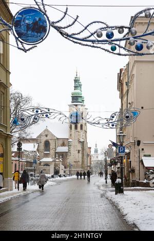 Cracovia, Polonia - 17 gennaio 2021: Inverno nevoso a Cracovia, poche persone che camminano su Grodzka Street. Decorazione di Natale Foto Stock