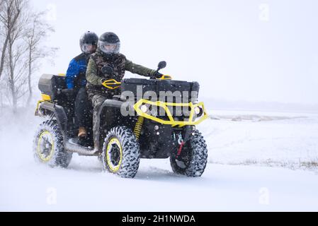 Guida con quad in inverno sulla neve Foto Stock