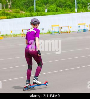 La ragazza sportswoman corre sugli sci a rullo sull'asfalto Foto Stock