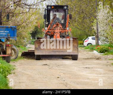 Krasnodar, Russia - 19 aprile 2018: Livellatrice su una strada sterrata. Riparazione stradale con aggiunta di macerie. Foto Stock