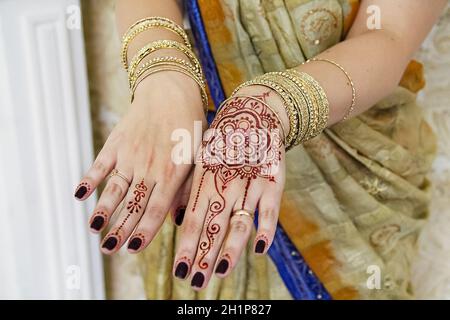 Mani indiane in braccialetti d'oro e tatuaggi. Foto Stock