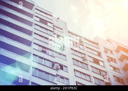 Un uomo su una corda scende dal tetto di un edificio su una corda attraverso una finestra. Foto Stock