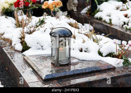 luce grave su una tomba coperta di neve con fiori dentro lo sfondo Foto Stock