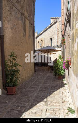 Tavoli da ristoranti nella stretta strada della famosa antica città di Erice, Sicilia, Sicilia Foto Stock