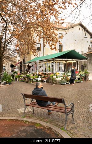 Udine, Italia. 2 febbraio 2021. Un uomo seduto su una panchina nella stagione invernale in una piazza nel centro storico di Udine Foto Stock