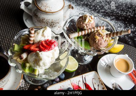 Dessert italiano - cialde croccanti con gelato, formaggio cremoso e marmellata. Pezzi di frutta per dessert. Concetto - alimento dolce, problema di obesità. Foto Stock
