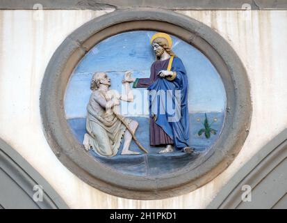 Opere di Misericordia, terracotta invetriata tondo di Andrea della Robbia, situata tra due archi del vecchio Ospedale di San Paolo, a Firenze, Italia Foto Stock