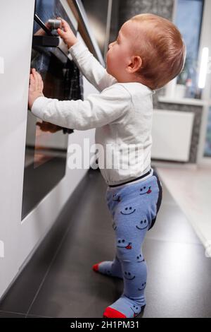 Bambino piccolo che gioca con stufa elettrica in cucina Foto Stock