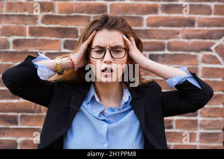Terribile mal di testa. Ritratto di cercando stanco business donna in smart casual toccando la testa con le mani Foto Stock