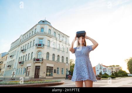 Giovane donna in abiti estivi con dispositivo di VR per esterno Foto Stock