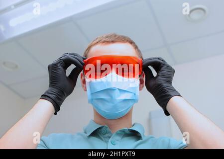 Il dentista indossa occhiali di sicurezza di colore arancione. Foto macro. Spazio di copia. Foto Stock