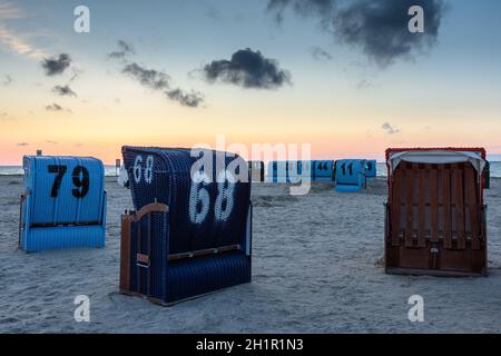 Sedie da spiaggia in vimini sulla spiaggia di Neuharlingersiel al crepuscolo, Frisia orientale, bassa Sassonia, Germania Foto Stock