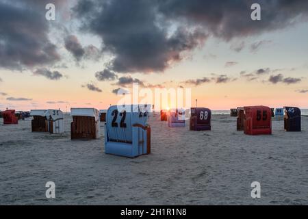 Sedie da spiaggia in vimini sulla spiaggia di Neuharlingersiel al tramonto, Frisia orientale, bassa Sassonia, Germania Foto Stock