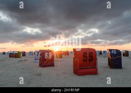 Sedie da spiaggia in vimini sulla spiaggia di Neuharlingersiel al tramonto, Frisia orientale, bassa Sassonia, Germania Foto Stock