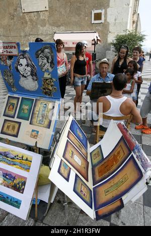 Artista di strada e pittore in un mercato di strada in un vicolo nel centro storico di Taormina in provincia di Sicilia in Italia. Italia, Sicilia, Foto Stock