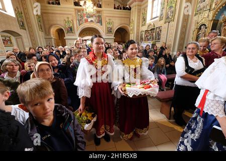 La gente vestita in regionali tradizionali costumi folk in chiesa durante la Santa Messa il giorno del Ringraziamento in Stitar, Croazia Foto Stock