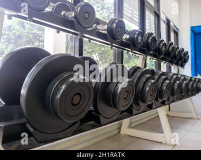 set di manubri. Chiudi molte manubri in metallo su rack nel centro fitness sportivo Foto Stock