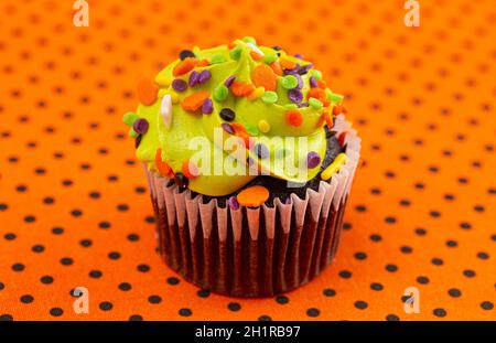 Halloween Cupcakes a tema con Sprinkles su un tavolo arancione e nero Foto Stock