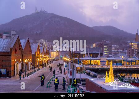 Paesaggio urbano degli storici magazzini in mattoni rossi e del Monte Hakodate al crepuscolo a Hakodate, Hokkaido Giappone in inverno Foto Stock