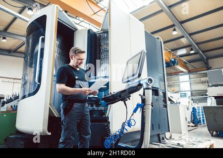 Lavoratore dell'industria del metallo che lavora un moderno tornio cnc Foto Stock