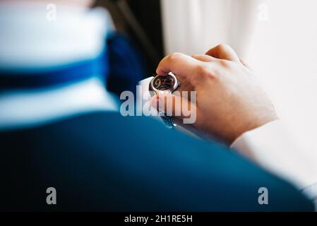 lo sposo in una tuta blu guarda l'orologio indossato sulla mano sinistra Foto Stock