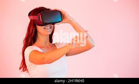 Donna in realtà virtuale che tende la mano e tocca qualcosa con il dito. Concetto di dispositivo indossabile digitale moderno che cambia la percezione del surr Foto Stock
