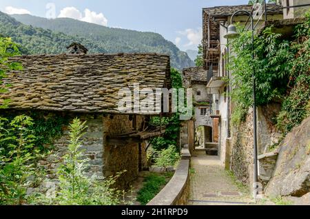 Pittoresco e stretto passaggio attraverso vecchie case tradizionali, girato in una luminosa giornata estiva a Fontainemore, Lys Valley, Aosta, Italia Foto Stock