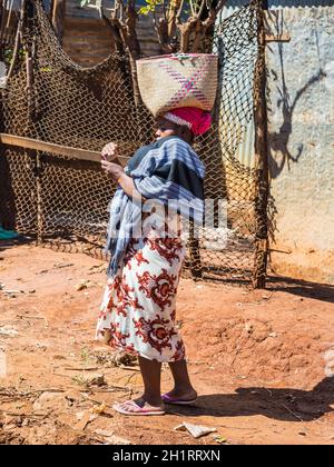 Antsiranana, Madagascar - Dicembre 20, 2015: Unidentified donna malgascia guarda nel telefono e borsa per trasporto sul suo capo di Antsiranana (Diego Suarez), Foto Stock